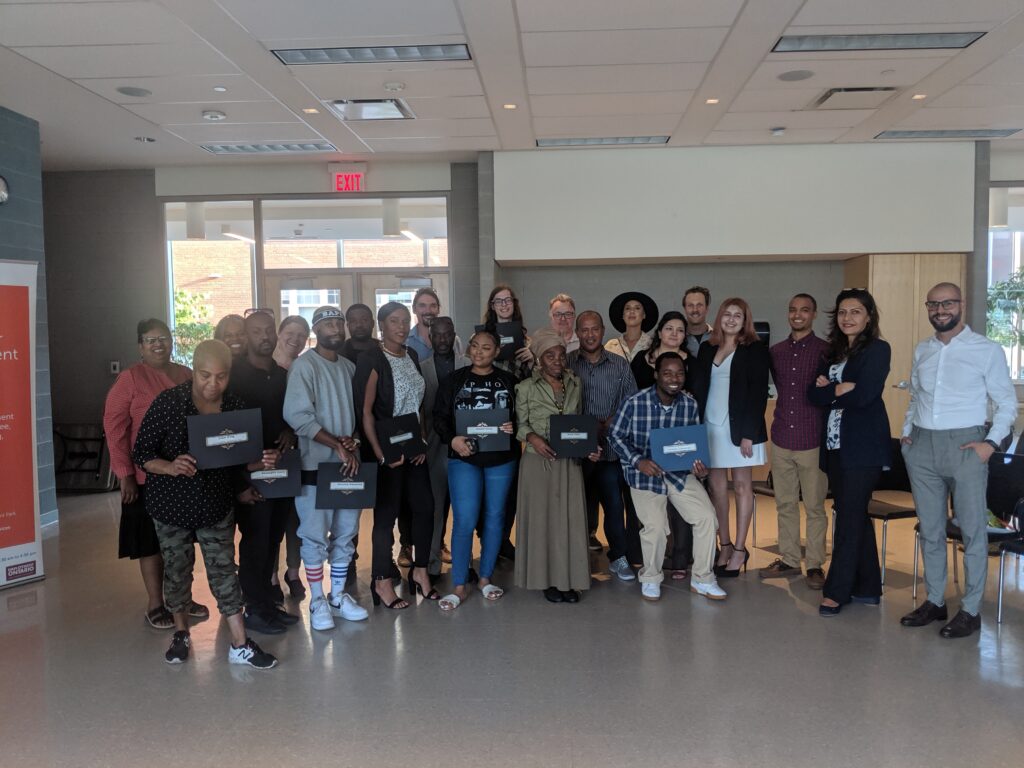 graduates from employment services programs pose together with their diplomas