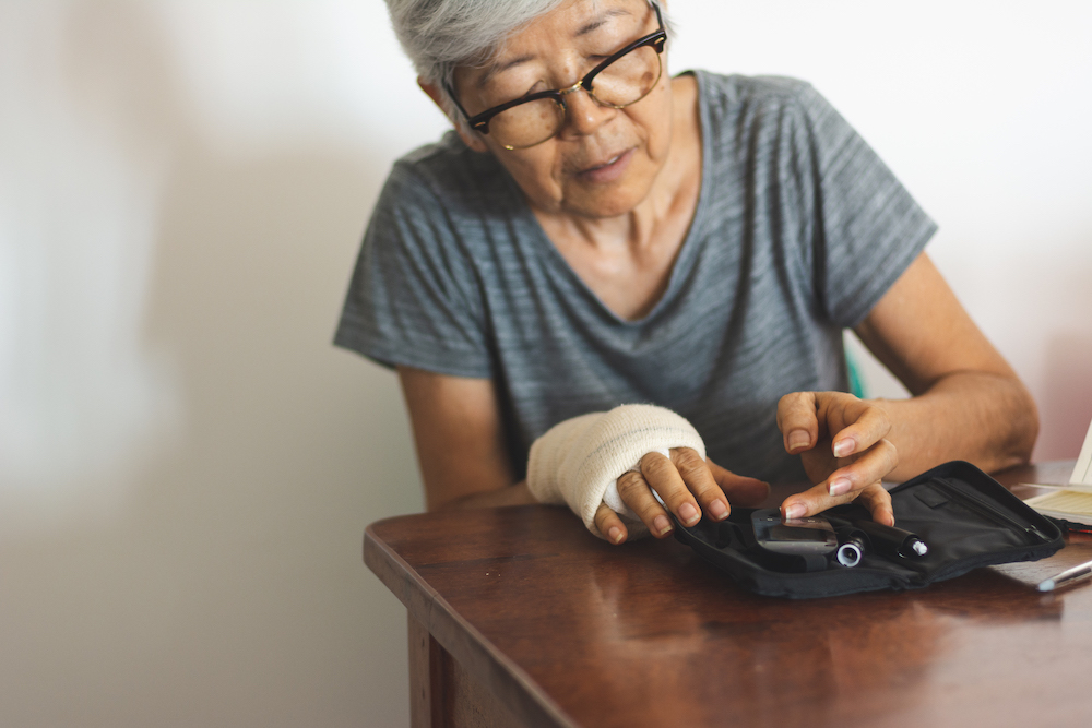 Senior woman with glucometer checking blood sugar level at home